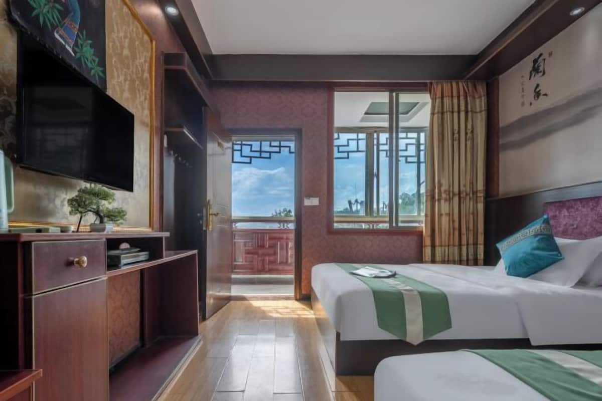 Une chambre d’hôtel avec un lit, une télévision, un bureau et une fenêtre donnant sur un paysage agréable.