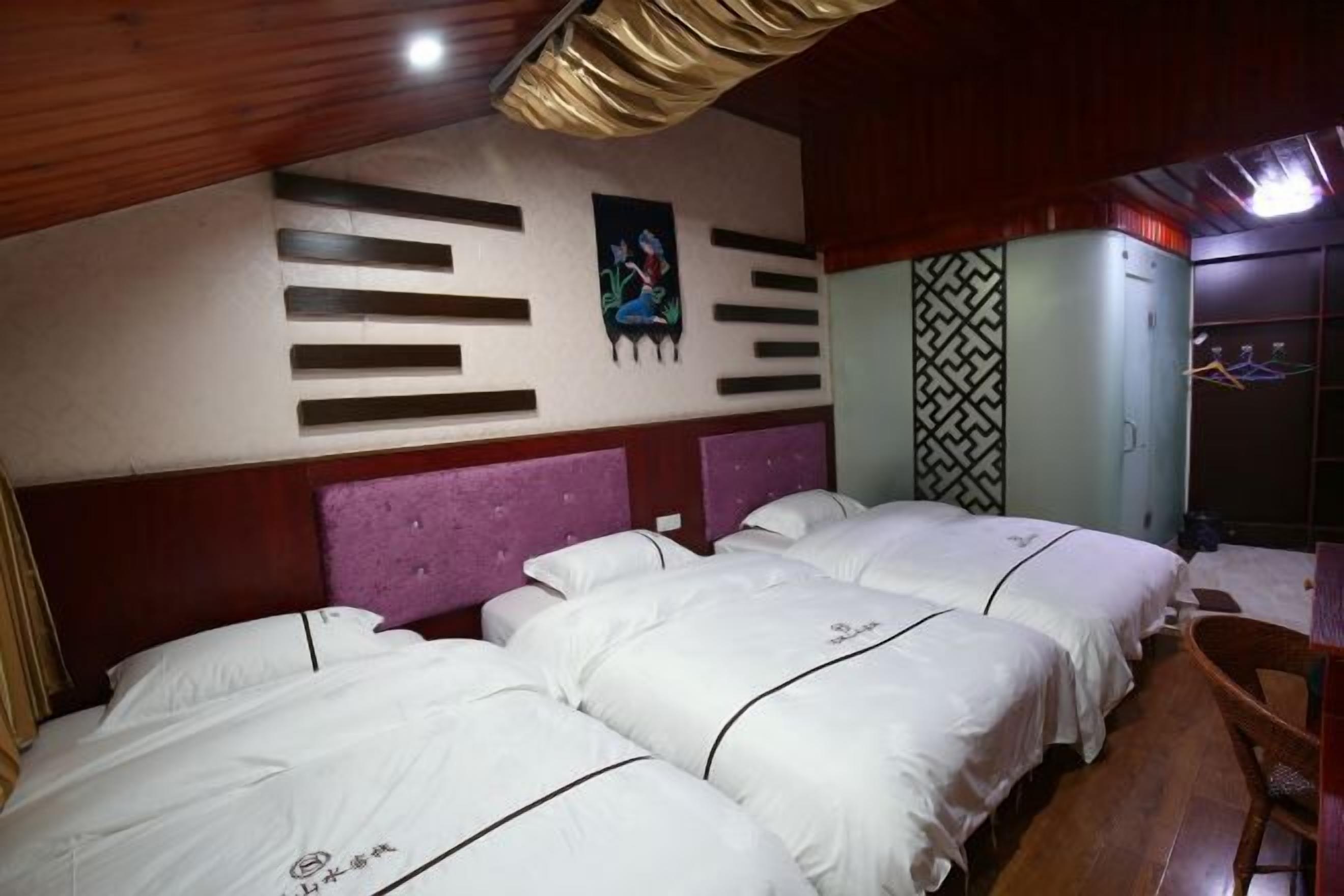 Quarto de hotel com teto de madeira, cama com roupa de cama branca, cabeceira roxa e parede com padrão geométrico.