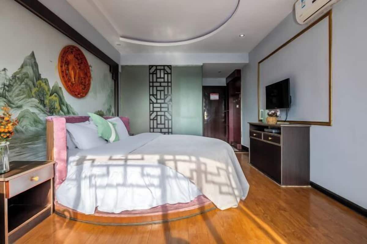 Une chambre moderne avec un grand lit, une télévision et une fresque murale décorative.