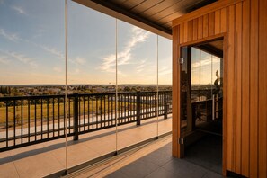 A balcony with a view of a cityscape, a wooden door, and a metal railing.