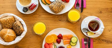 A breakfast setting with various food items and drinks on a wooden table.