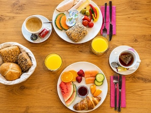 A breakfast setting with various food items and drinks on a wooden table.
