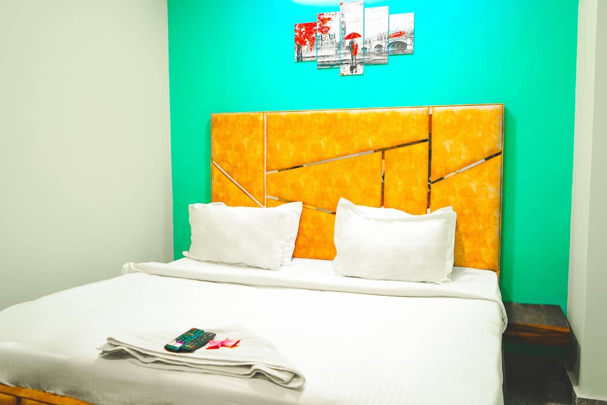 Una cama con cabecera amarilla, almohadas blancas y un control remoto sobre la cama.