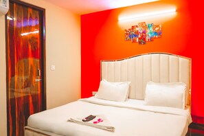 Une chambre d’hôtel avec un lit, une table de chevet, une télécommande et une œuvre d’art murale.