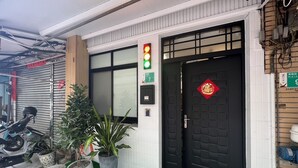 A building entrance with a black door, a red Chinese character symbol, and a green traffic light above the door. - mimi cat house (Tainan)