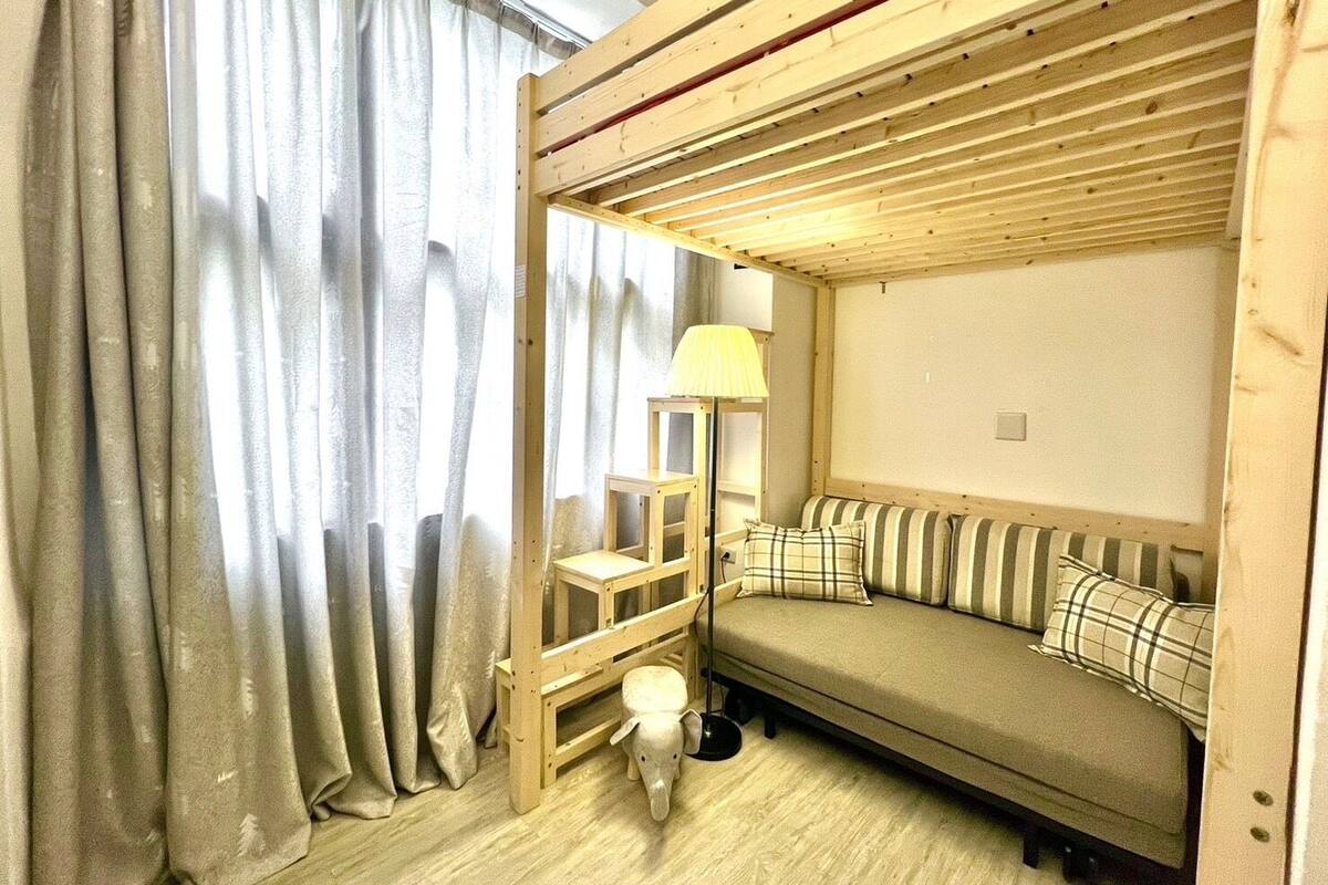 A cozy room with a wooden bunk bed, a sofa with striped cushions, a lamp, and a small pig figurine.