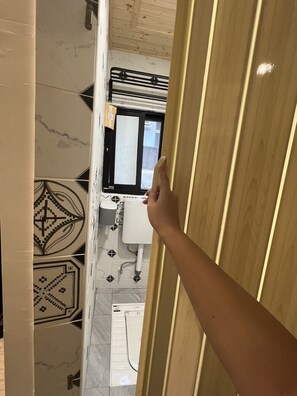 A bathroom with a toilet, sink, and window.