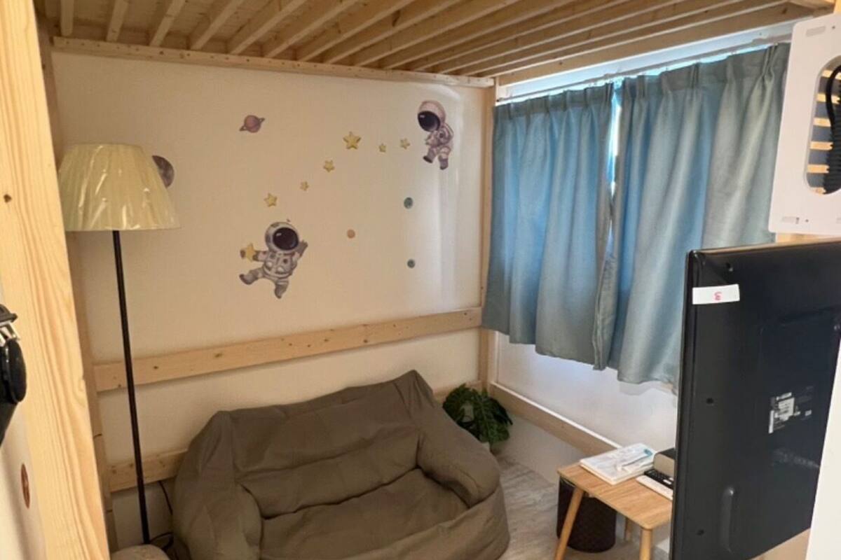 A cozy room with a bunk bed, a bean bag chair, a small table, and a TV.