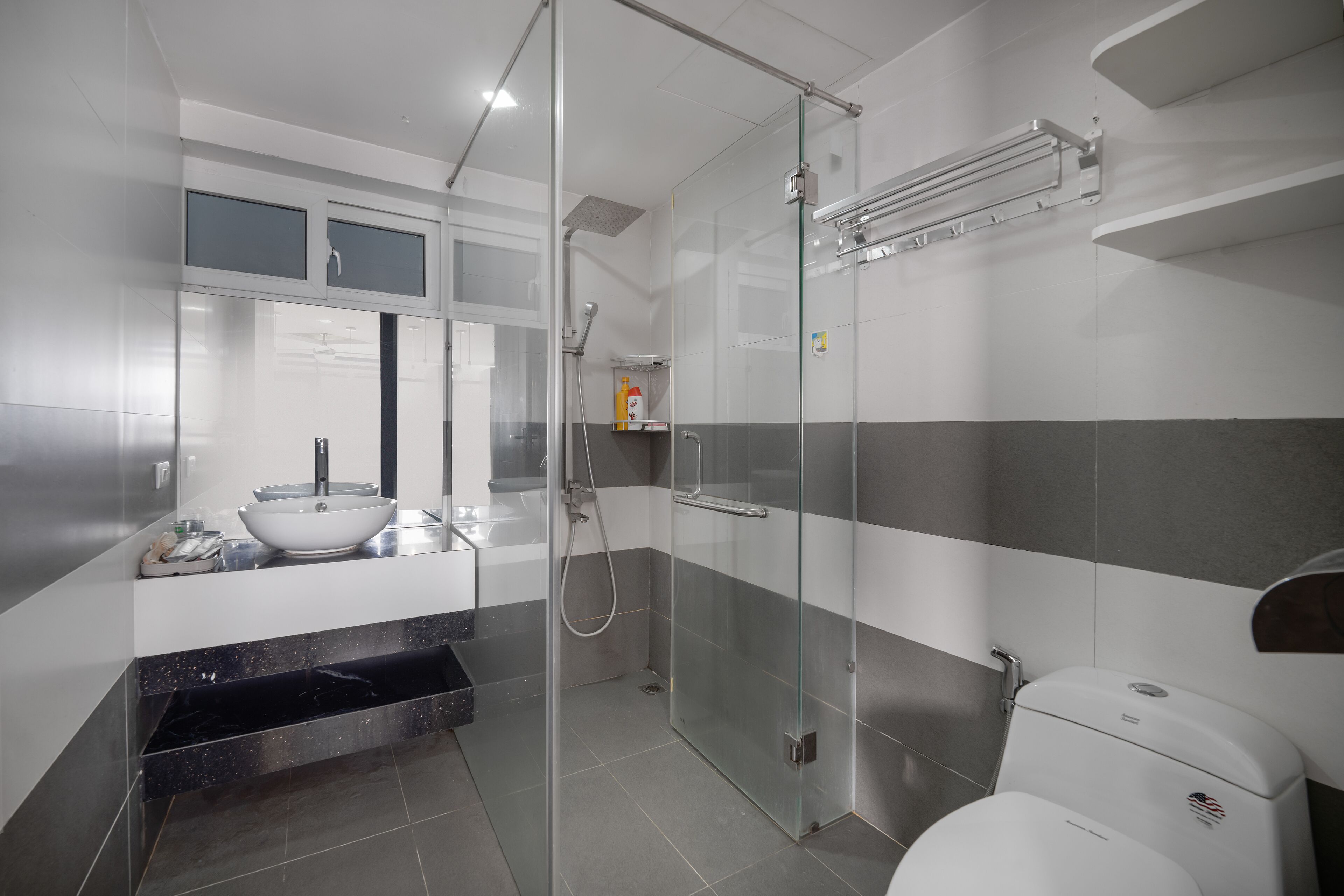 A modern bathroom with a glass-enclosed shower, a white sink, and a toilet.