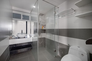 Ein modernes Badezimmer mit einer Duschkabine, einem weißen Waschbecken und einer Toilette.