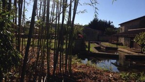A traditional bamboo structure with a water channel, surrounded by bamboo trees and a clear sky. - COUNTRY HOUSE WITH LARGE GARDEN + PRIVATE POOL + RIVER (La Grimaudière)