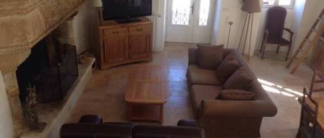 A living room with a fireplace, a sofa, a television, and a door leading outside.