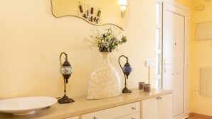 A bathroom with a beige vanity, a white sink, a vase with flowers, two wall-mounted lights, and a mirror. - Belle Vue by Interhome (Almuñécar)