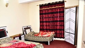 Een slaapkamer met twee bedden, een rood tapijt, een bed met een decoratief sprei en een zwart-rode gordijn.