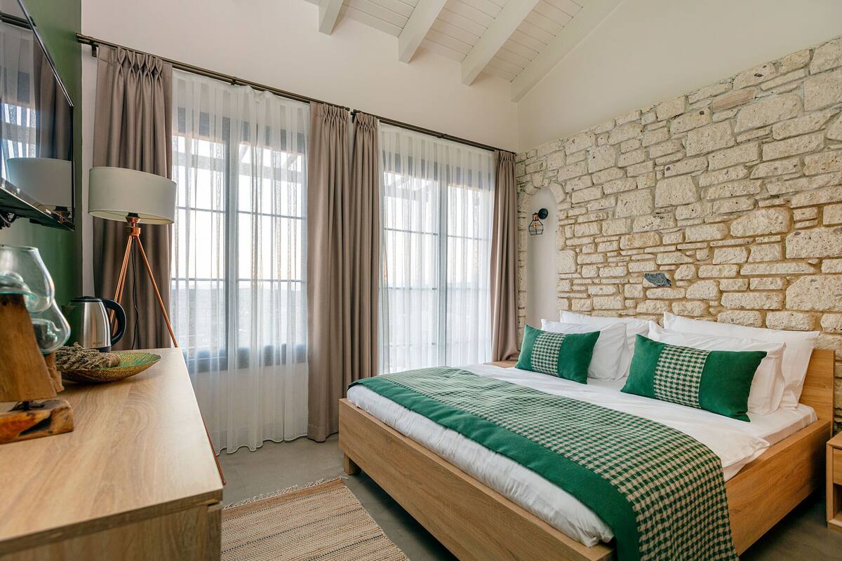 Un dormitorio con pared de piedra, cama de madera y escritorio con lámpara.