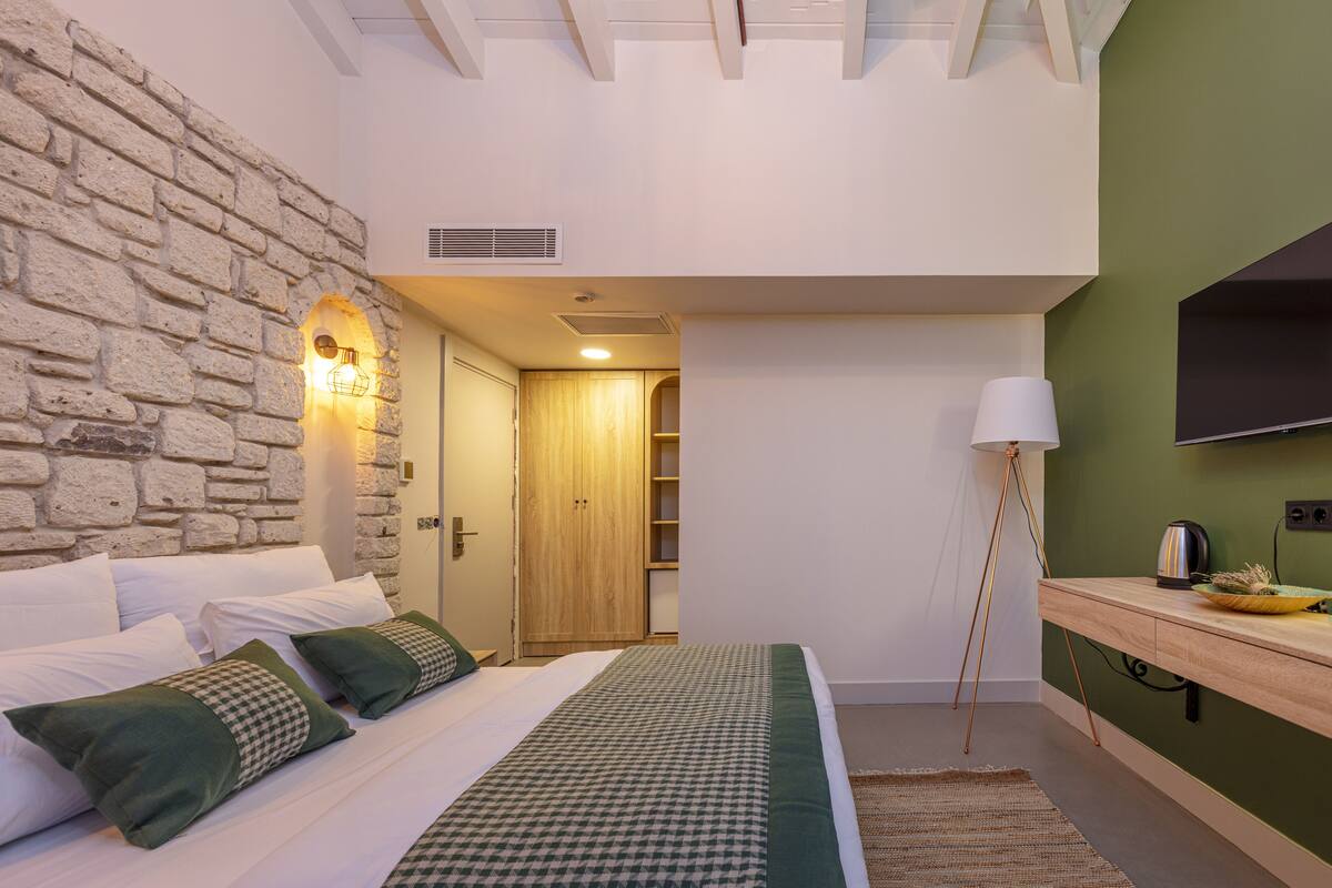 Un dormitorio con pared de piedra, un armario de madera, una lámpara de noche y un televisor de pantalla plana.