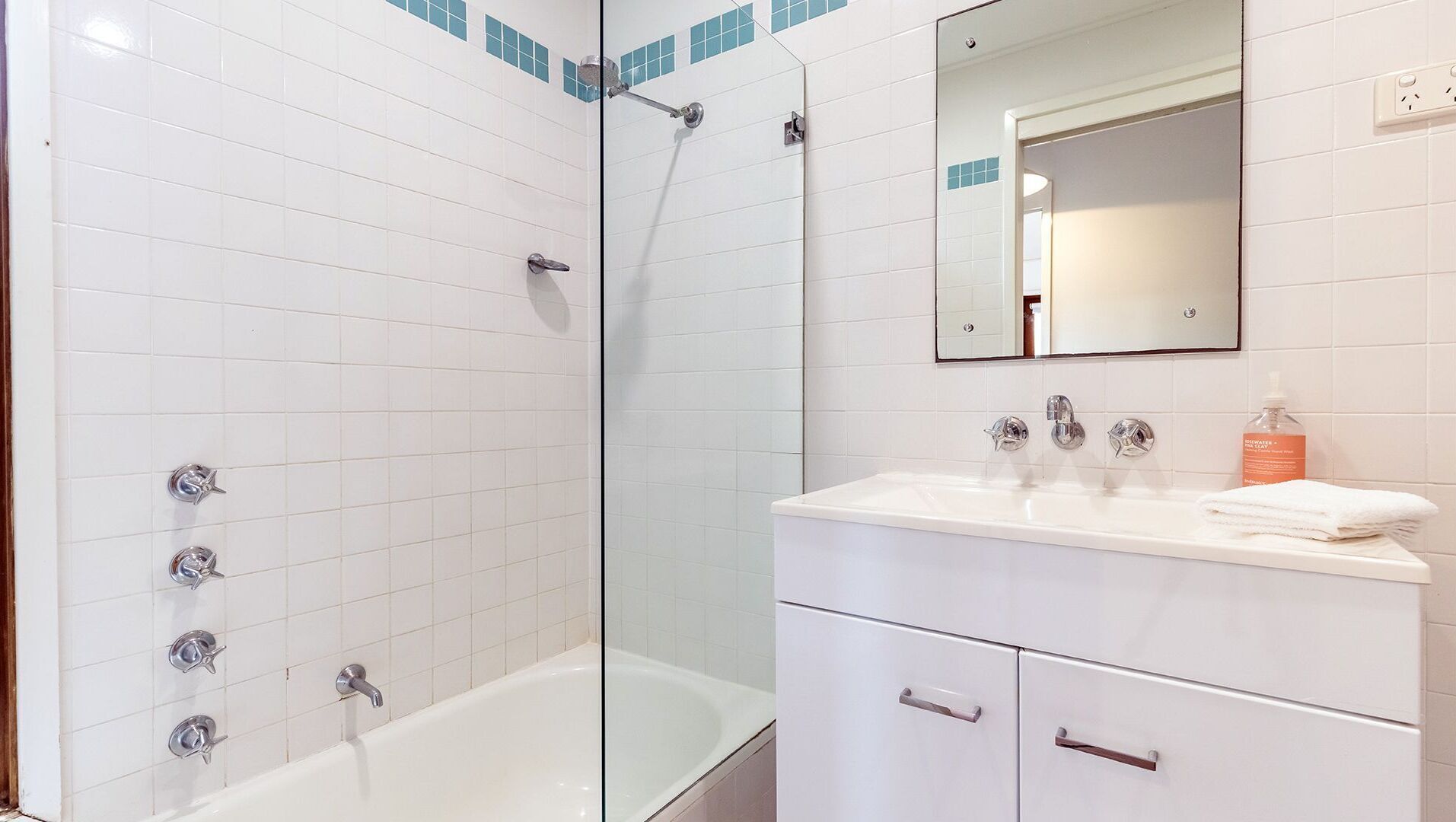 A modern bathroom with a glass-enclosed shower, a white bathtub, and a vanity with a mirror and sink.