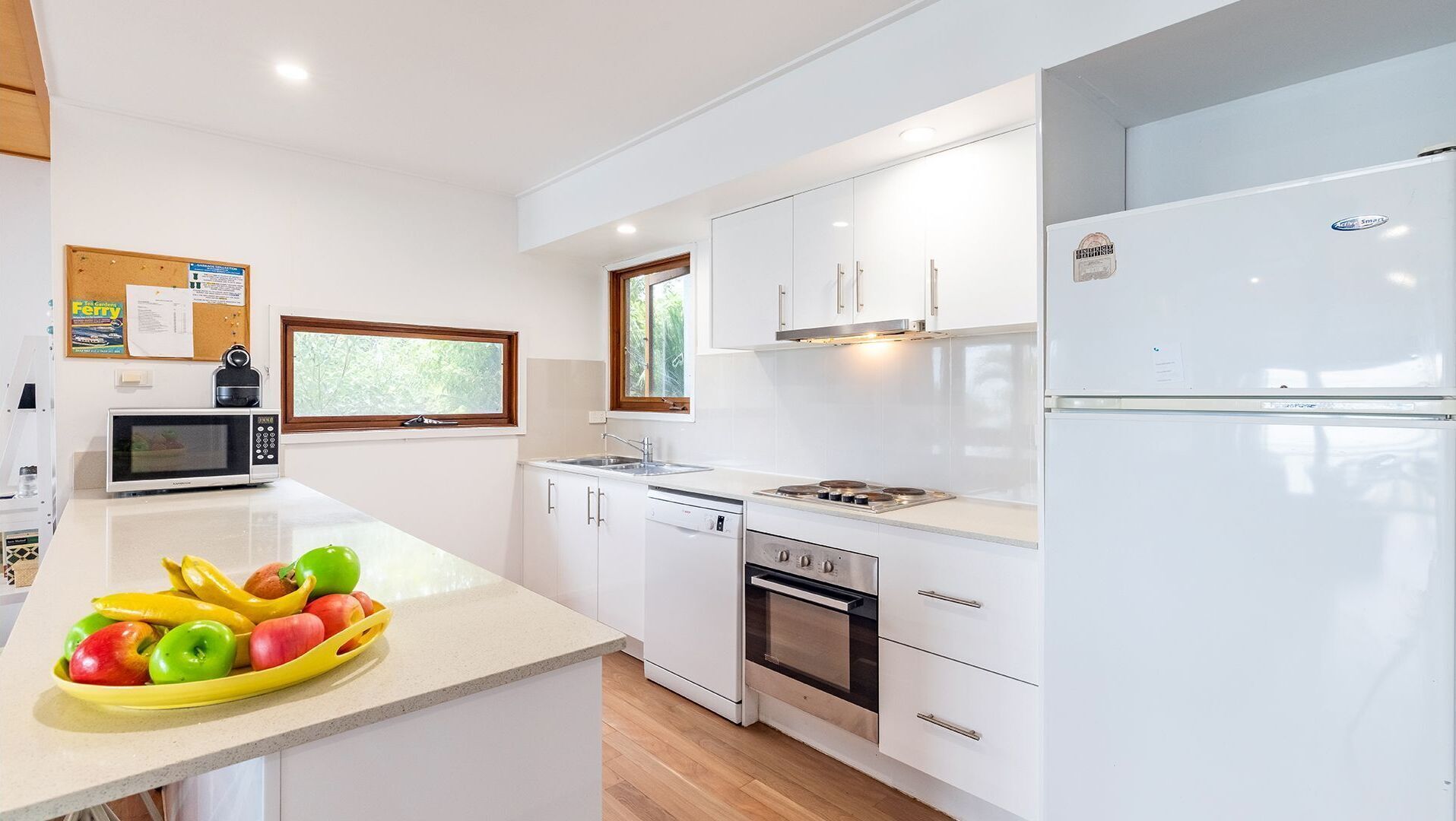 A modern kitchen with white cabinetry, a microwave, a stove, and a refrigerator.