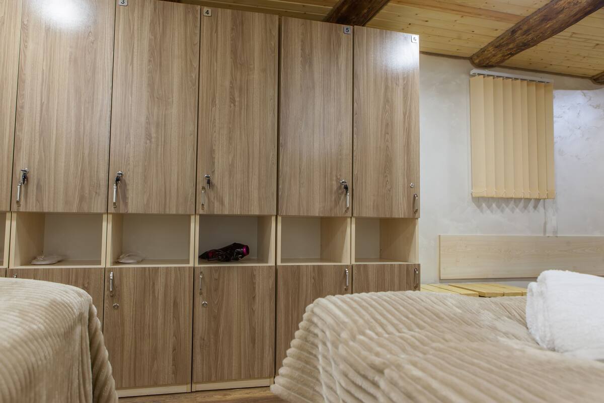 A room with wooden wardrobes, a bed, and a window with blinds.