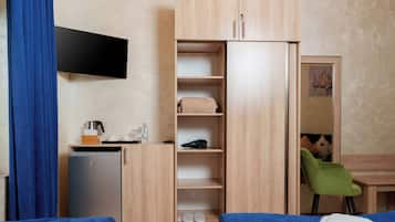 Une chambre d’hôtel équipée d’un lit, d’un bureau, d’une armoire, d’un petit réfrigérateur et d’une chaise.