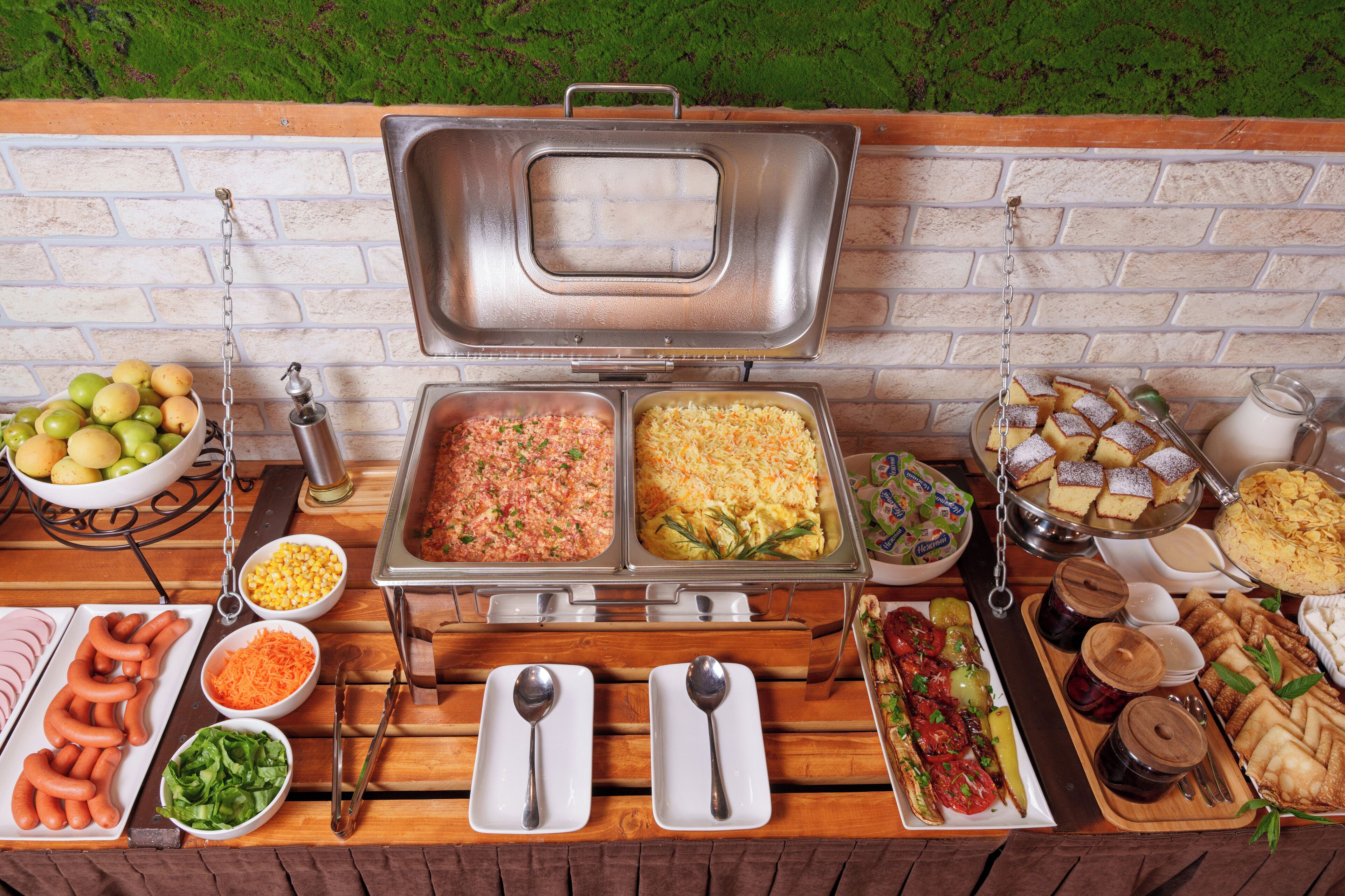 A buffet table with various food items and serving utensils.