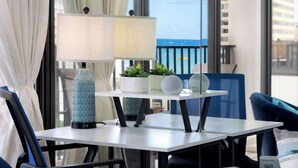 Een balkon met een tafel, stoelen, een lamp, een vaas en planten in potten.