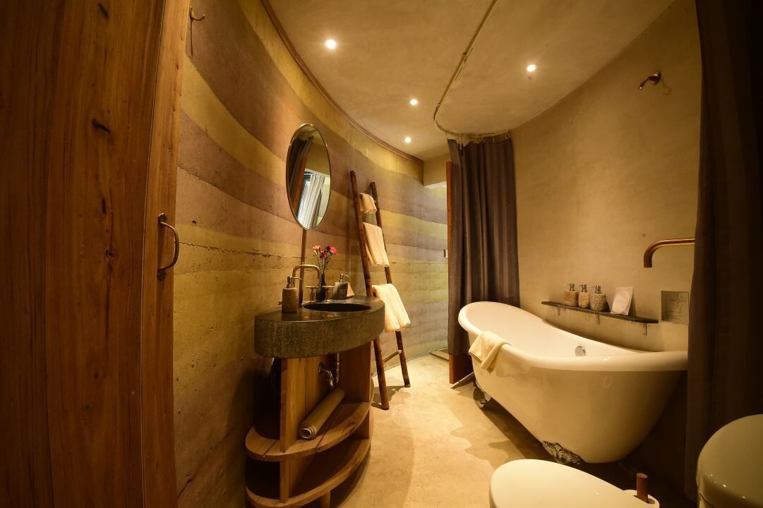 A modern bathroom with a wooden vanity, a freestanding bathtub, and a round mirror.
