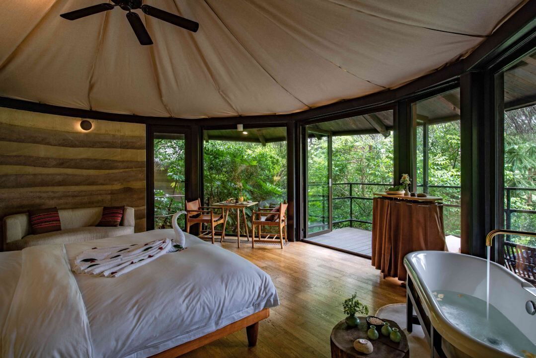 Un dormitorio amplio con una cama grande, una zona de estar con sillas, una mesa y una bañera.