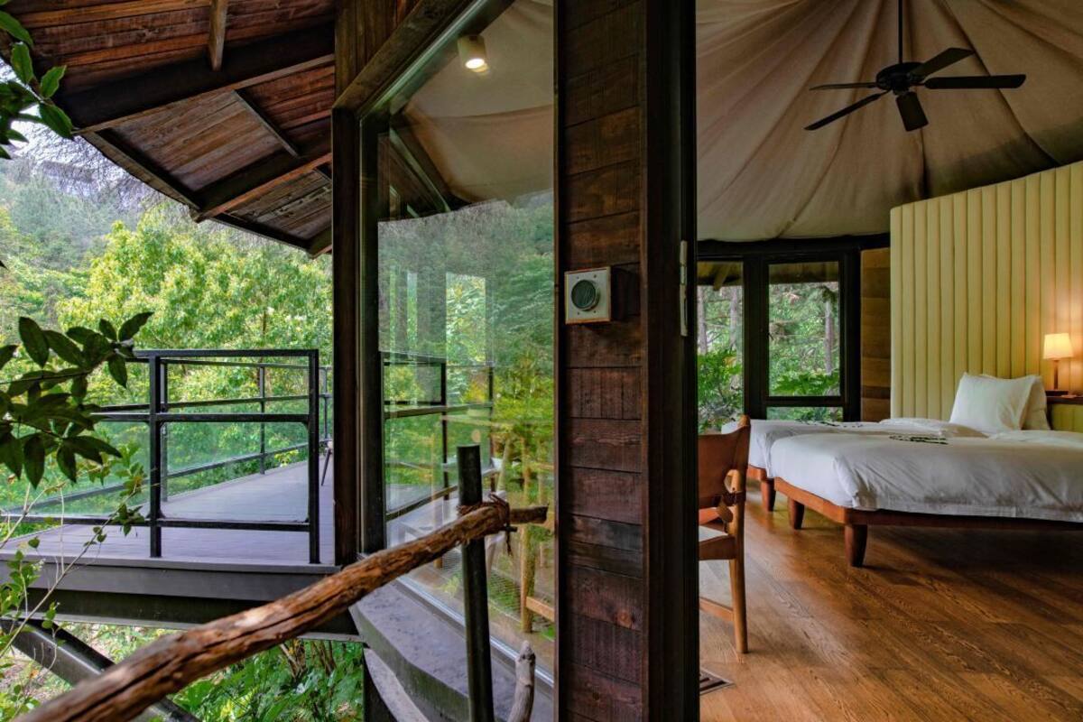 Une cabane en bois avec un balcon, un lit et un ventilateur de plafond.