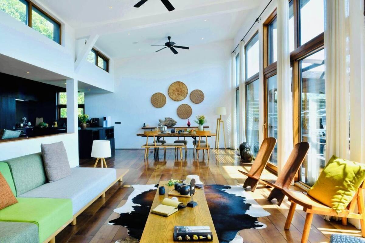 Un vaste espace de vie comprenant un canapé moderne, des chaises en bois, une table à manger et un tapis en peau de vache.