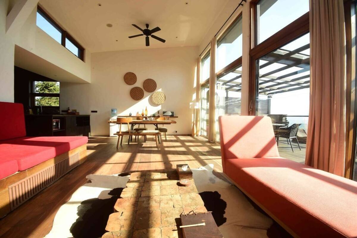 Un vaste espace de vie comprenant un canapé rouge, une table à manger en bois et un ventilateur de plafond.