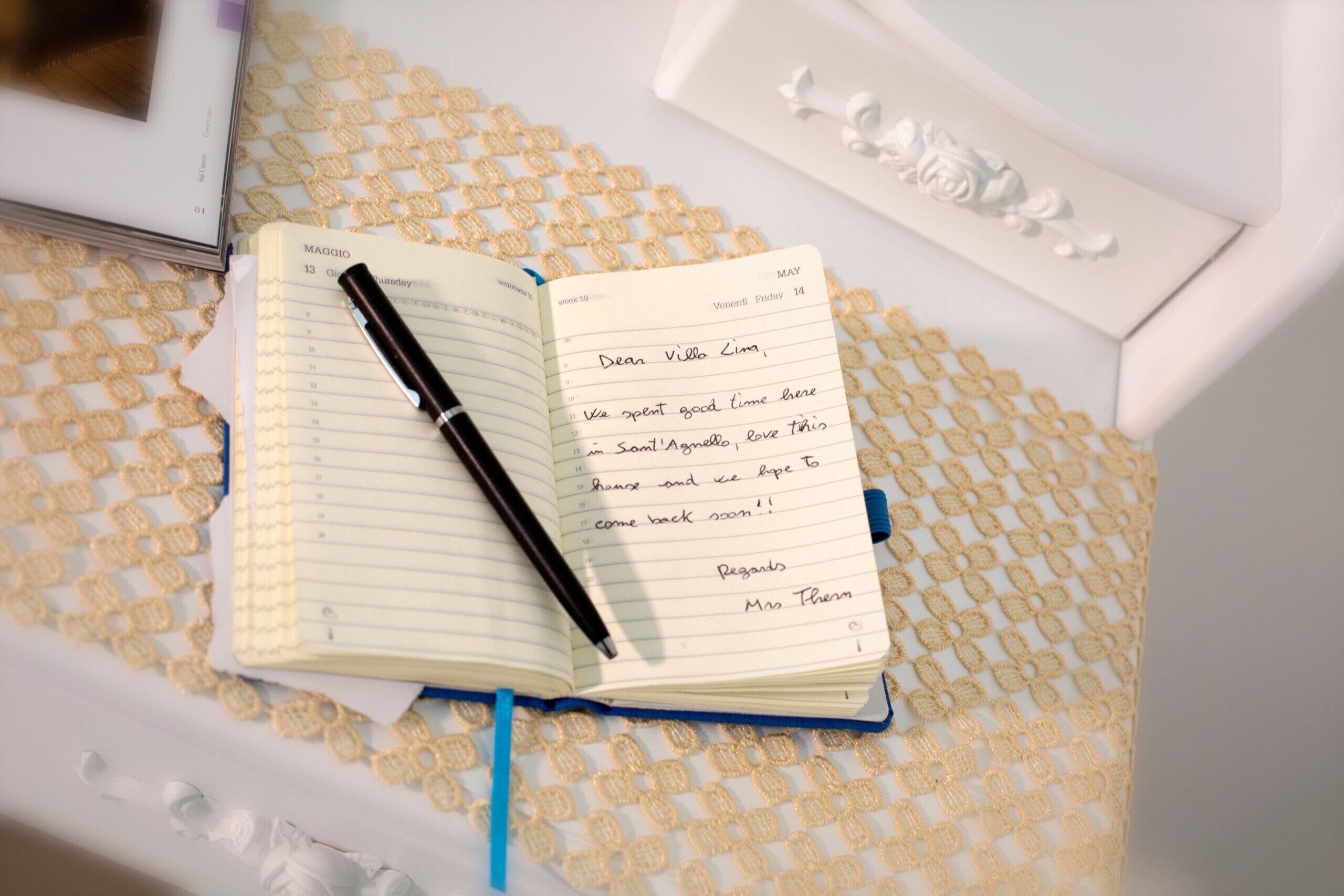 An open notebook with a handwritten note on a patterned fabric surface.