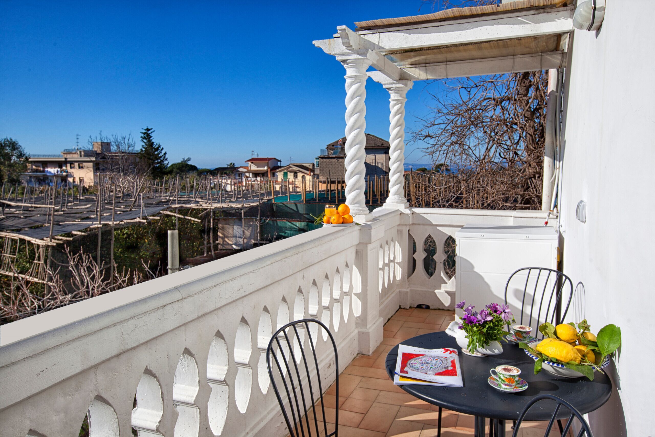 Un balcon avec une table dressée pour le dîner, une chaise et une vue sur les environs.
