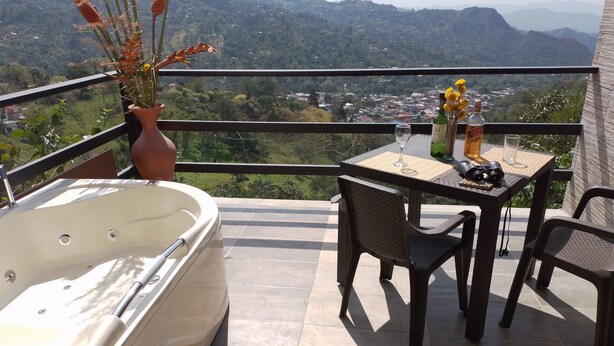 A balcony with a hot tub, a table with chairs, and a vase of flowers. - Captivating 4-bed Chalet Las Casitas en el Aire (San Francisco)