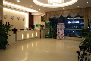 Zona de recepción de hotel con mostrador, un reloj y una ventana con cortinas.