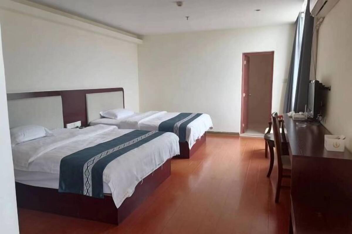 Et hotelværelse med to senge, et skrivebord og en stol.