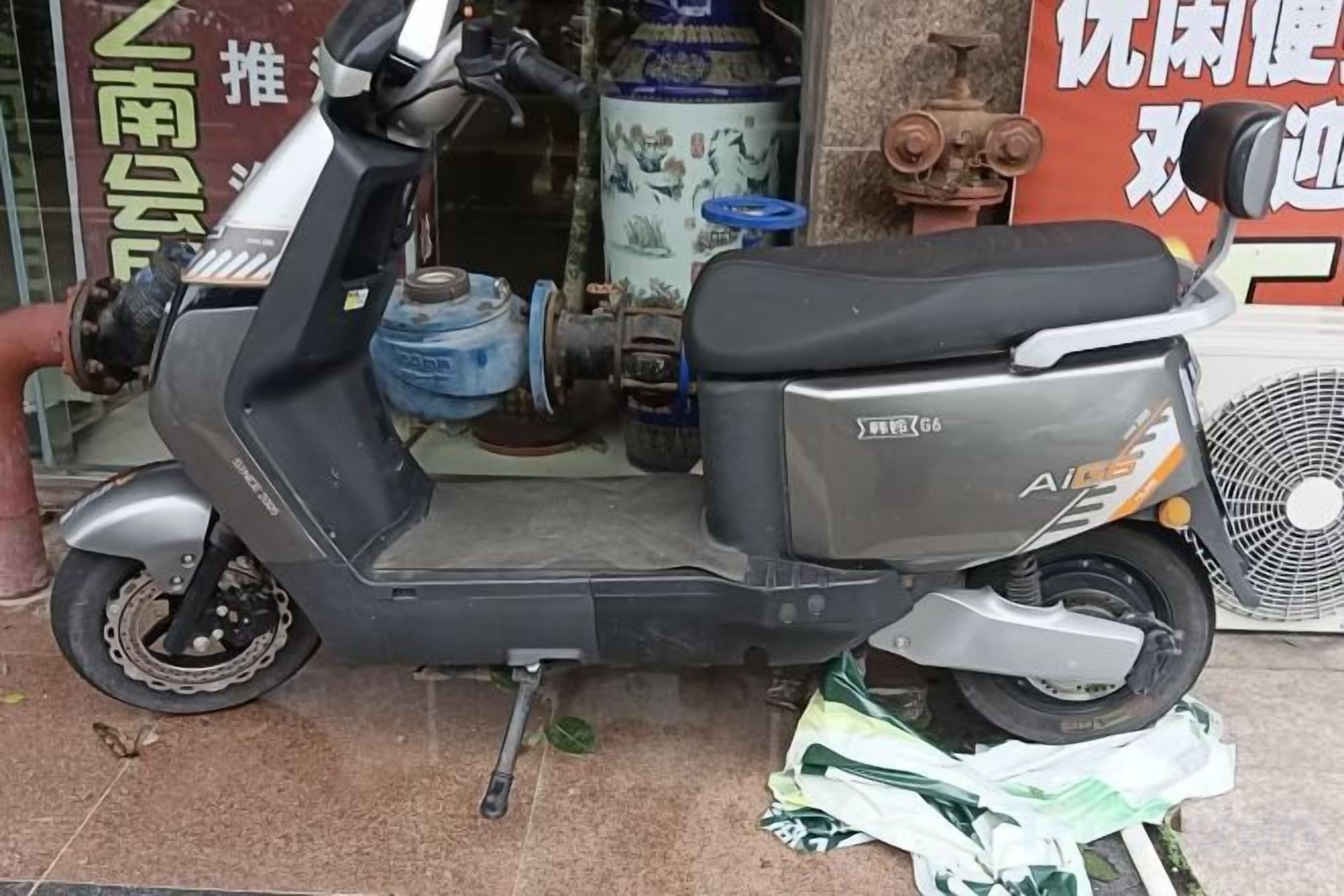 A stationary scooter parked in front of a building with a sign that includes Chinese characters.