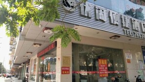 A storefront with a large panda logo, a sign indicating a sale, and a contact number. - Youxian Bianjie Hotel (Dongxing)