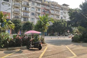 Un edificio de varios pisos con balcones, una moto estacionada y un paso de peatones.