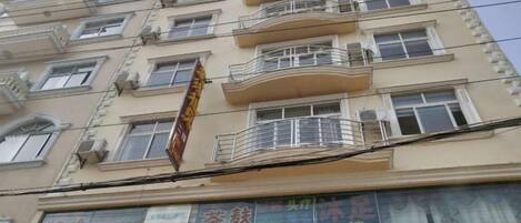 Un edificio de varios pisos con balcones, unidades de aire acondicionado y señalización.