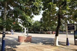 Calle arbolada con una barrera rayada y una señal de dirección.