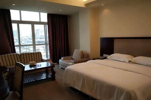 Une chambre d’hôtel avec un grand lit, un canapé, une petite table et une chaise.