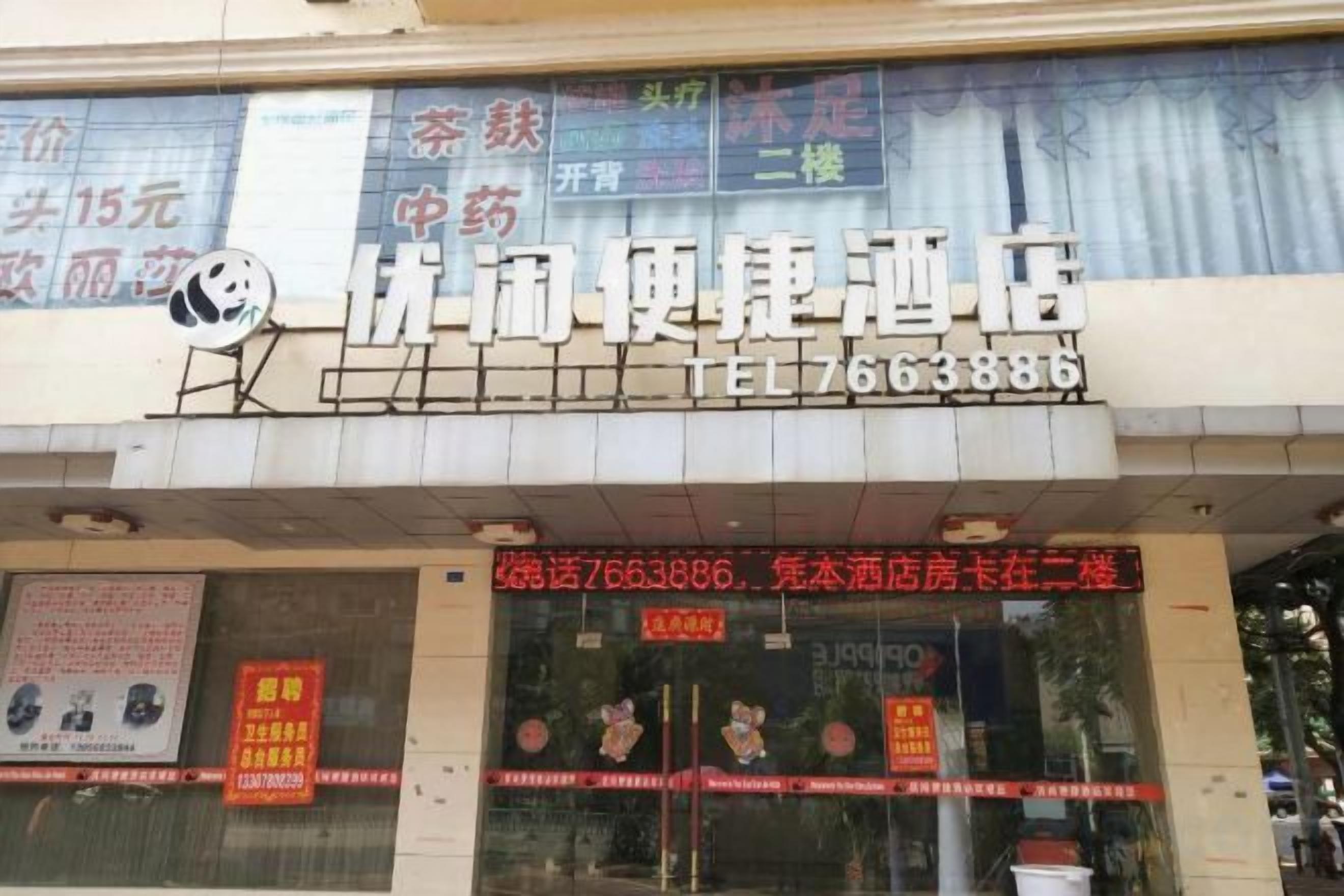 A hotel with a signboard displaying the name and contact number.