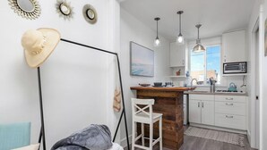 A compact kitchen with white cabinets, a wooden island, pendant lights, and a view of the outdoors.