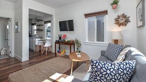 A modern living room with a grey sofa, patterned cushions, a coffee table, and a TV mounted on the wall. - 820.5 Portsmouth Relaunch · Between Mission Bay & Beach Patio, Firepit (San Diego)