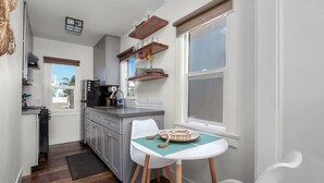 A compact kitchen with a dining area, a window with blinds, and a view of the outside. - 820.5 Portsmouth Relaunch · Between Mission Bay & Beach Patio, Firepit (San Diego)