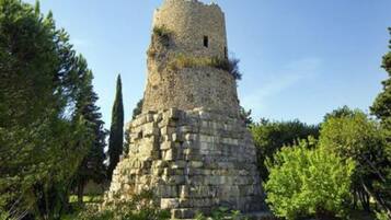 Una torre de piedra con un pequeño ventanal, rodeada de vegetación.
