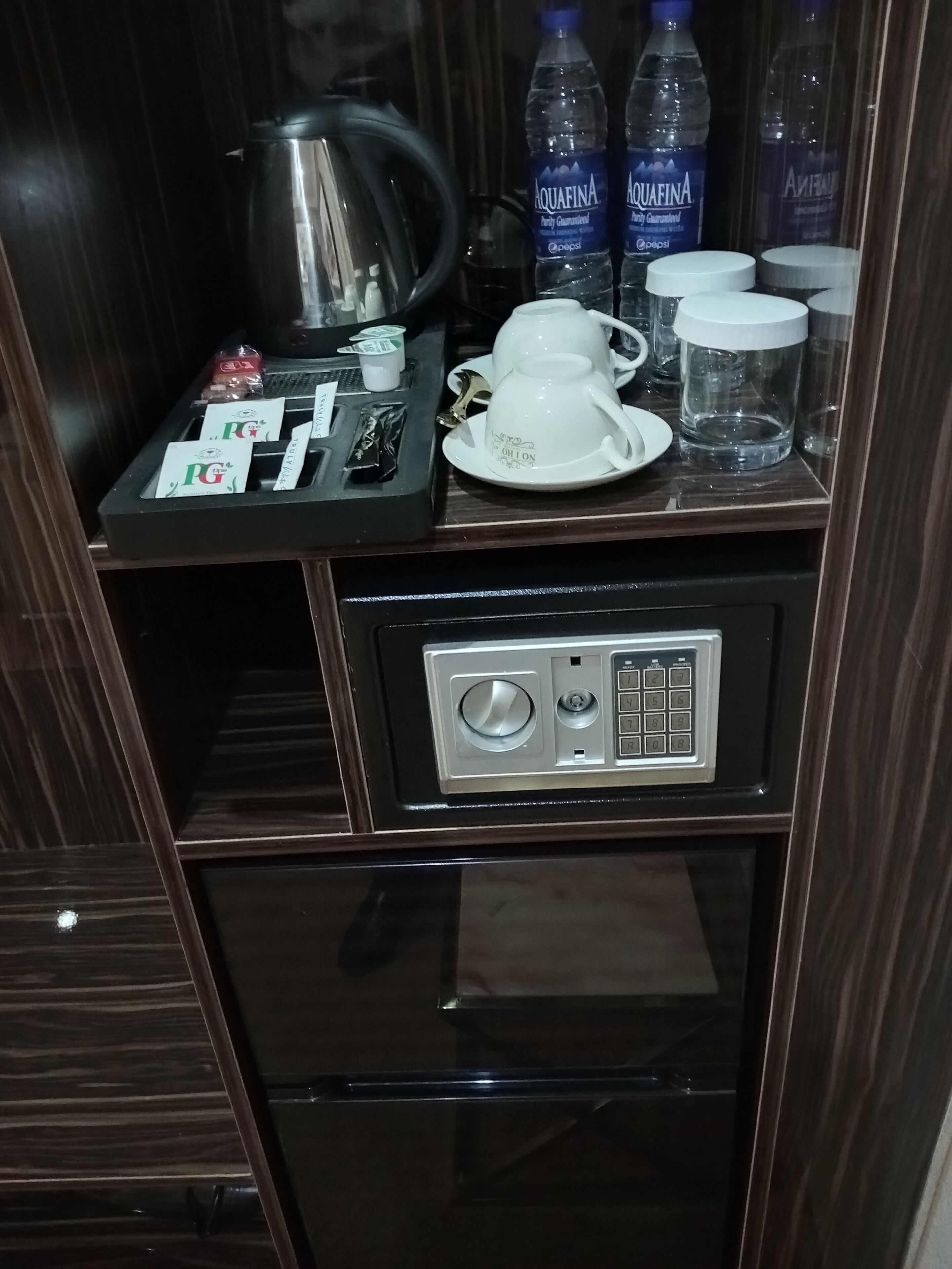 A minibar with a tea set, bottled water, and a coffee machine.