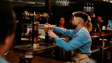A bartender pouring a drink from a tap into a glass.