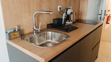 A modern kitchen with a stainless steel sink, a coffee machine, and a black tray.